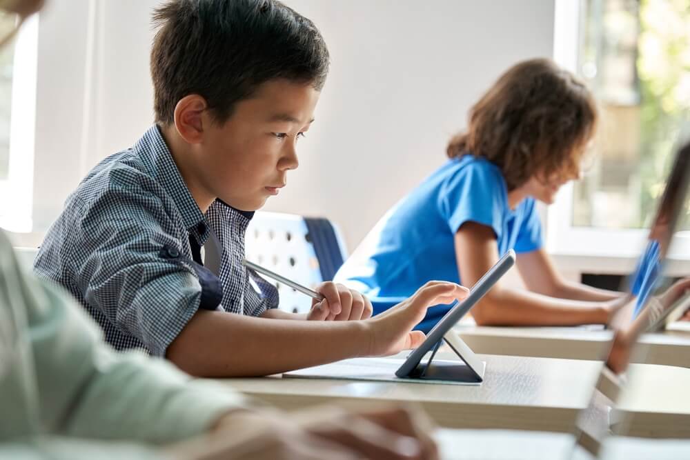 a young student using an iPad to do work in the classroom